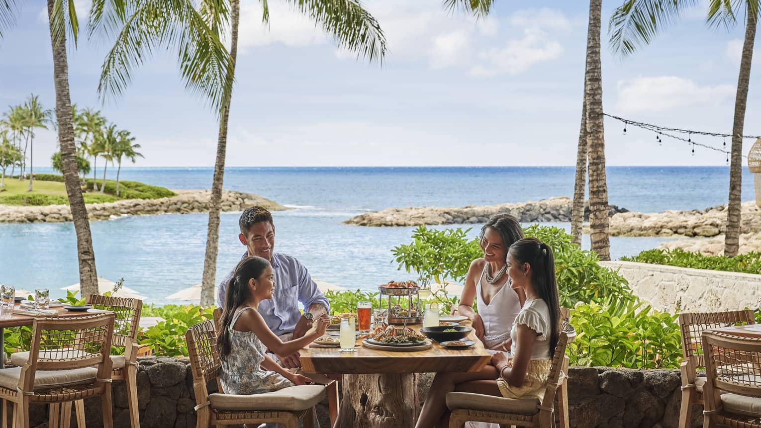 Family of four dining on Mina's Fish House beachfront patio