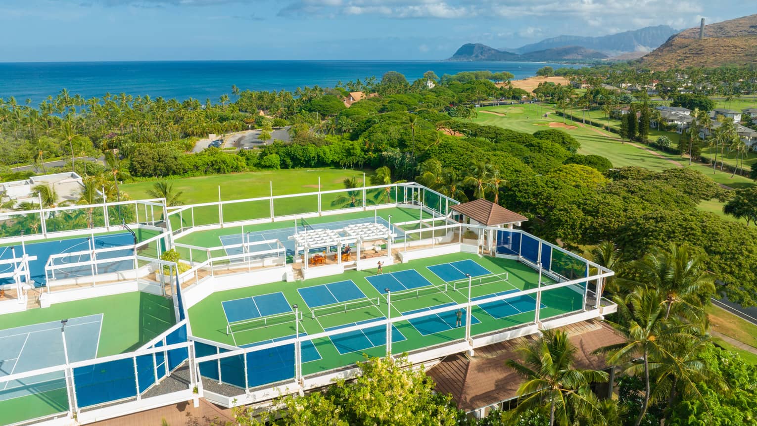 Tennis and pickleball courts at tropical resort with ocean in the distance