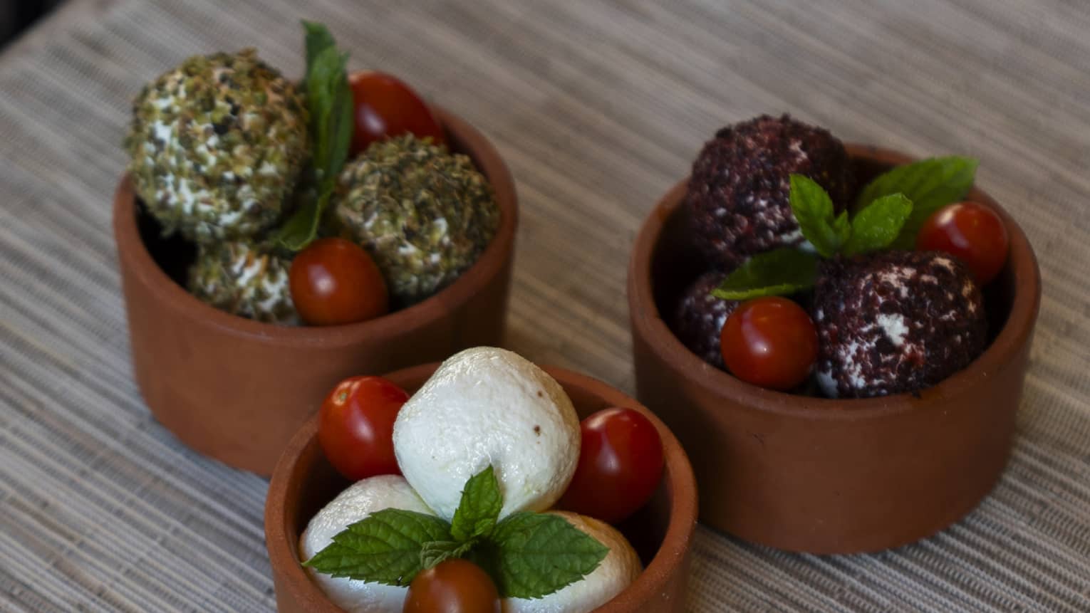 Dish trio of labneh balls garnished with mint leaves and grape tomatoes