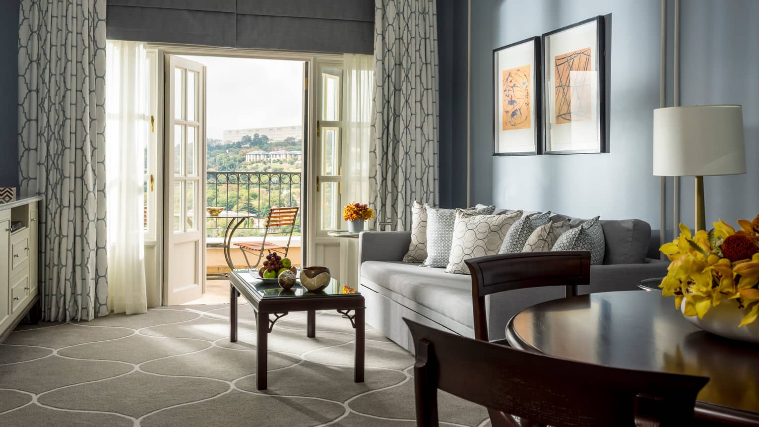 Panoramic-View One-Bedroom Suite round dining table, sofa and coffee table near open French doors to sunny balcony
