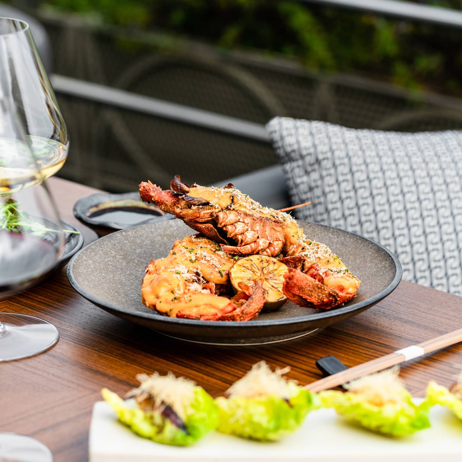 Spiny Lobster Thermidor on brown ceramic dish set on a wooden table with chopsticks