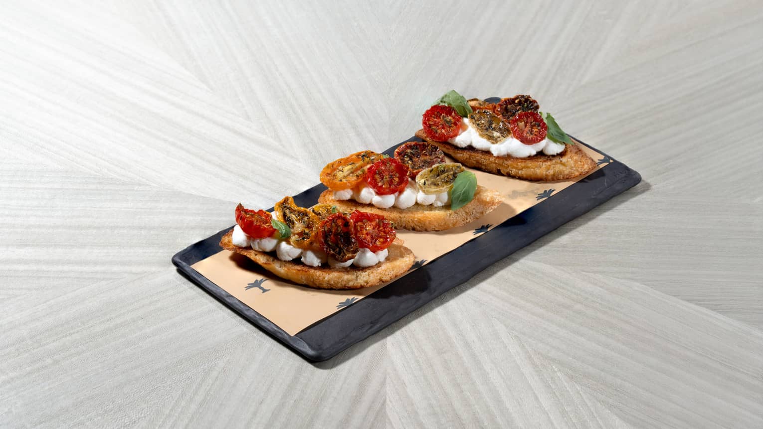 Three pieces of bruschetta served on a rectangular slate platter