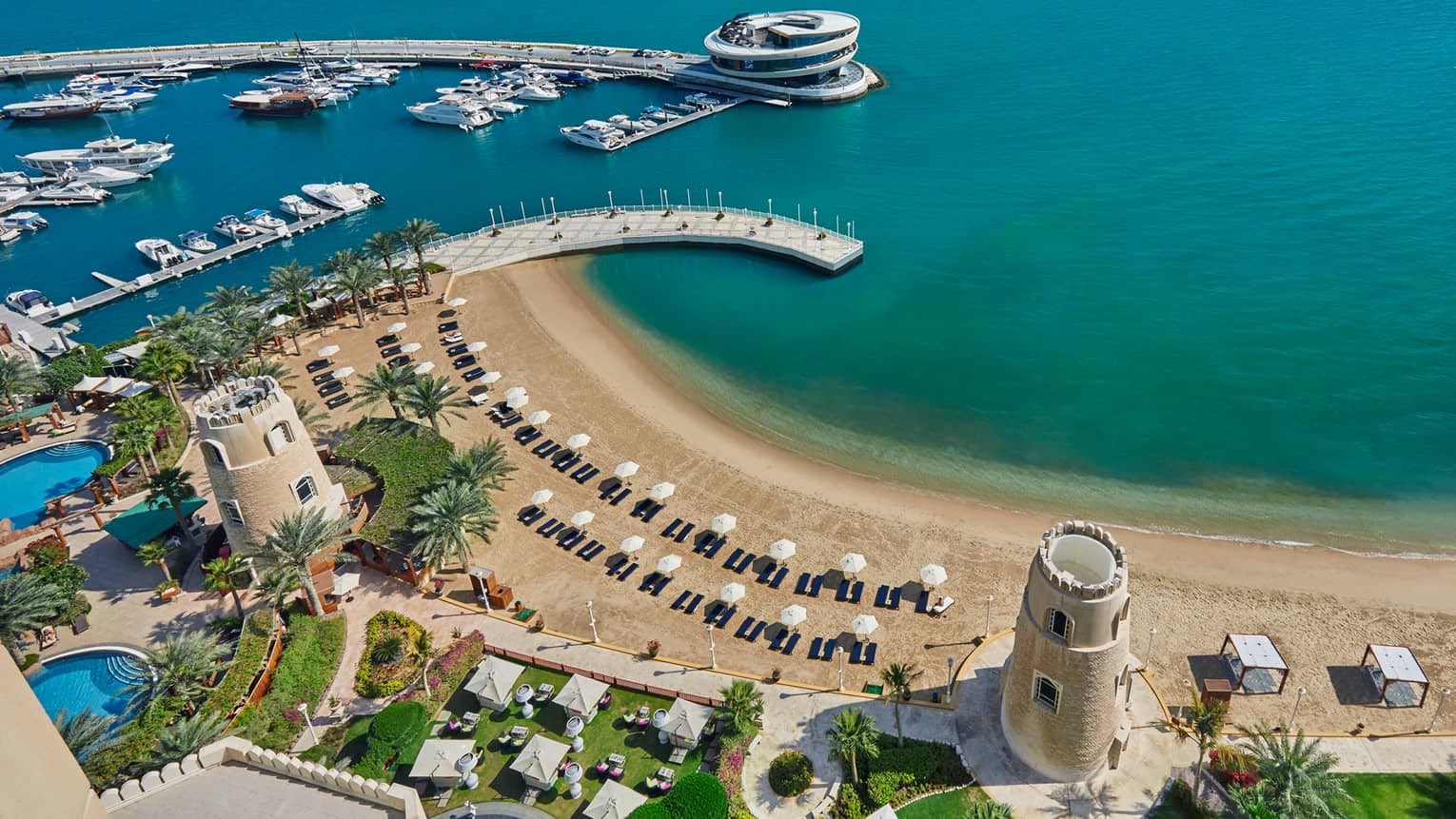 Aerial view of Four Seasons Doha pools and resort grounds, beach and gulf on sunny day