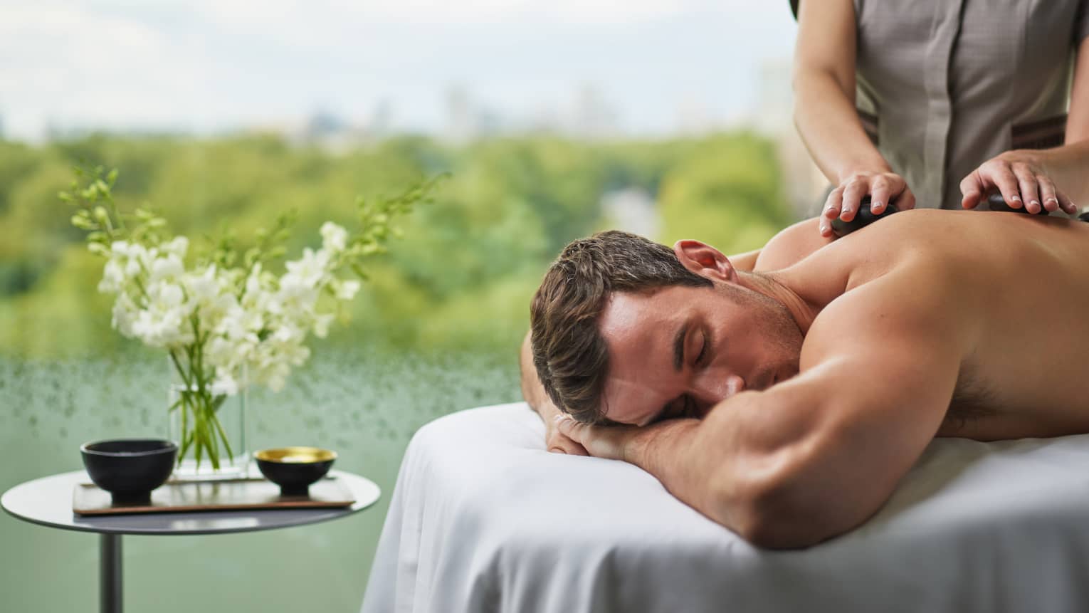 A man receives a massage next to a pond.