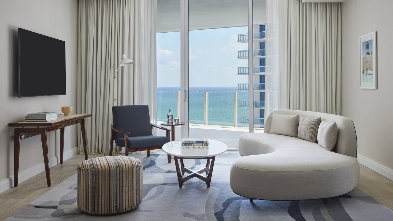 Living room with curved sofa, chair, table, ocean view