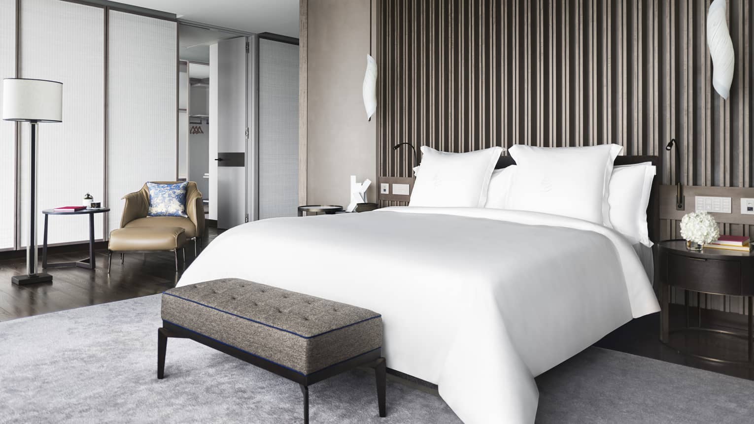 Hotel suite bedroom with white king bed and wooden accent wall/ceiling