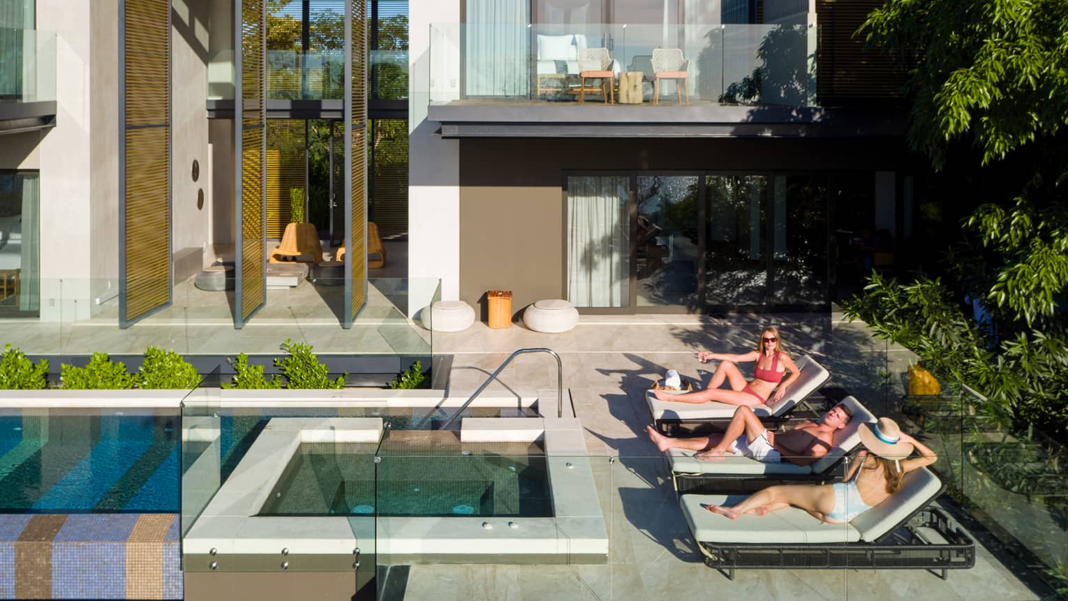 People on lounge chairs by outdoor pool