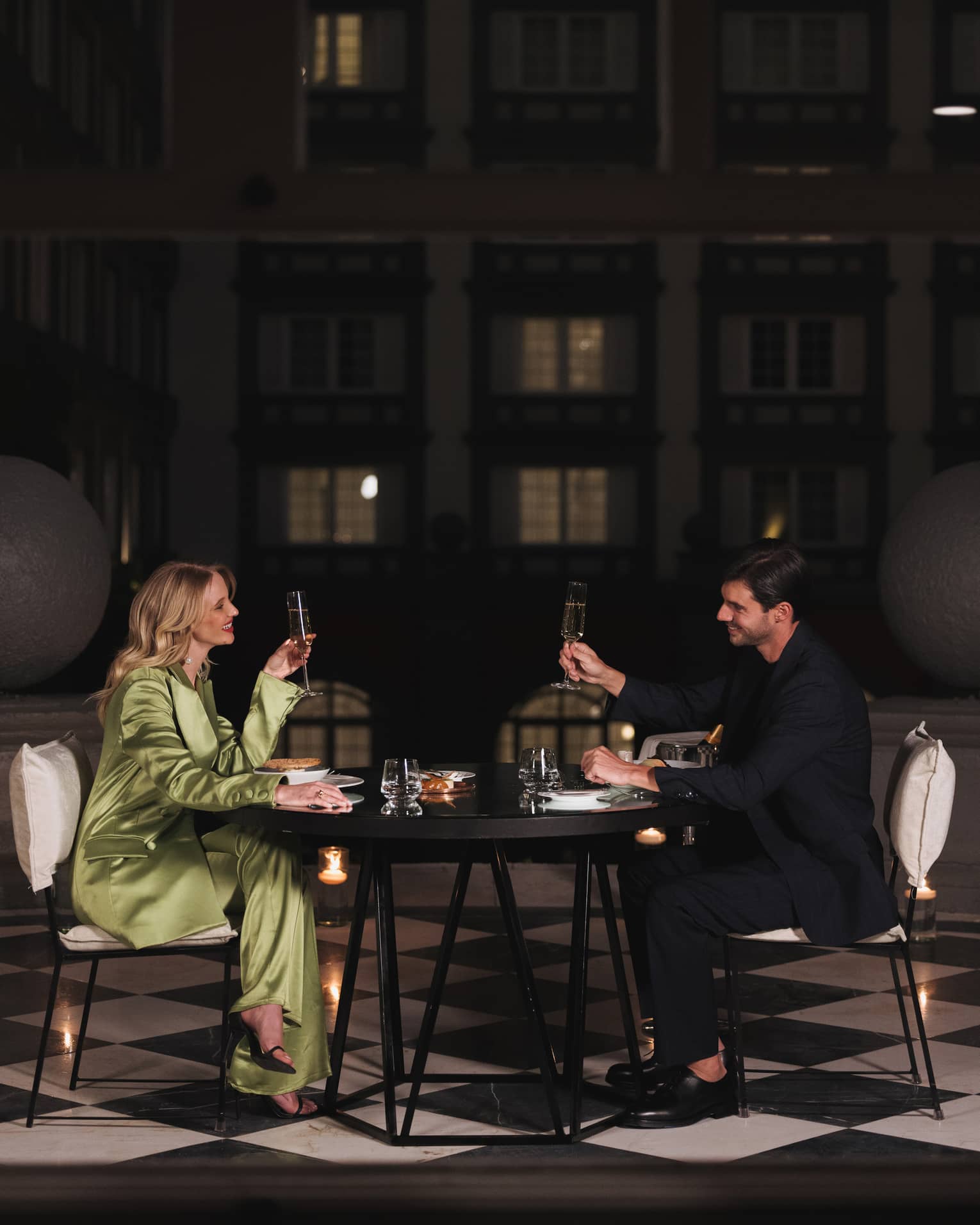 A man and woman drinking in a dimly lit room at a dark table.