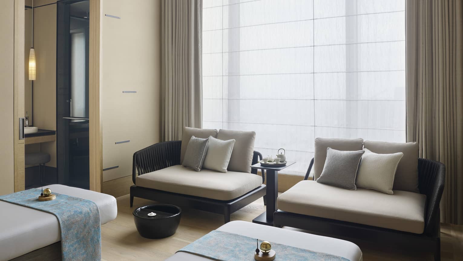 Couples Treatment Room, two spa treatment beds and small sofas under tall window