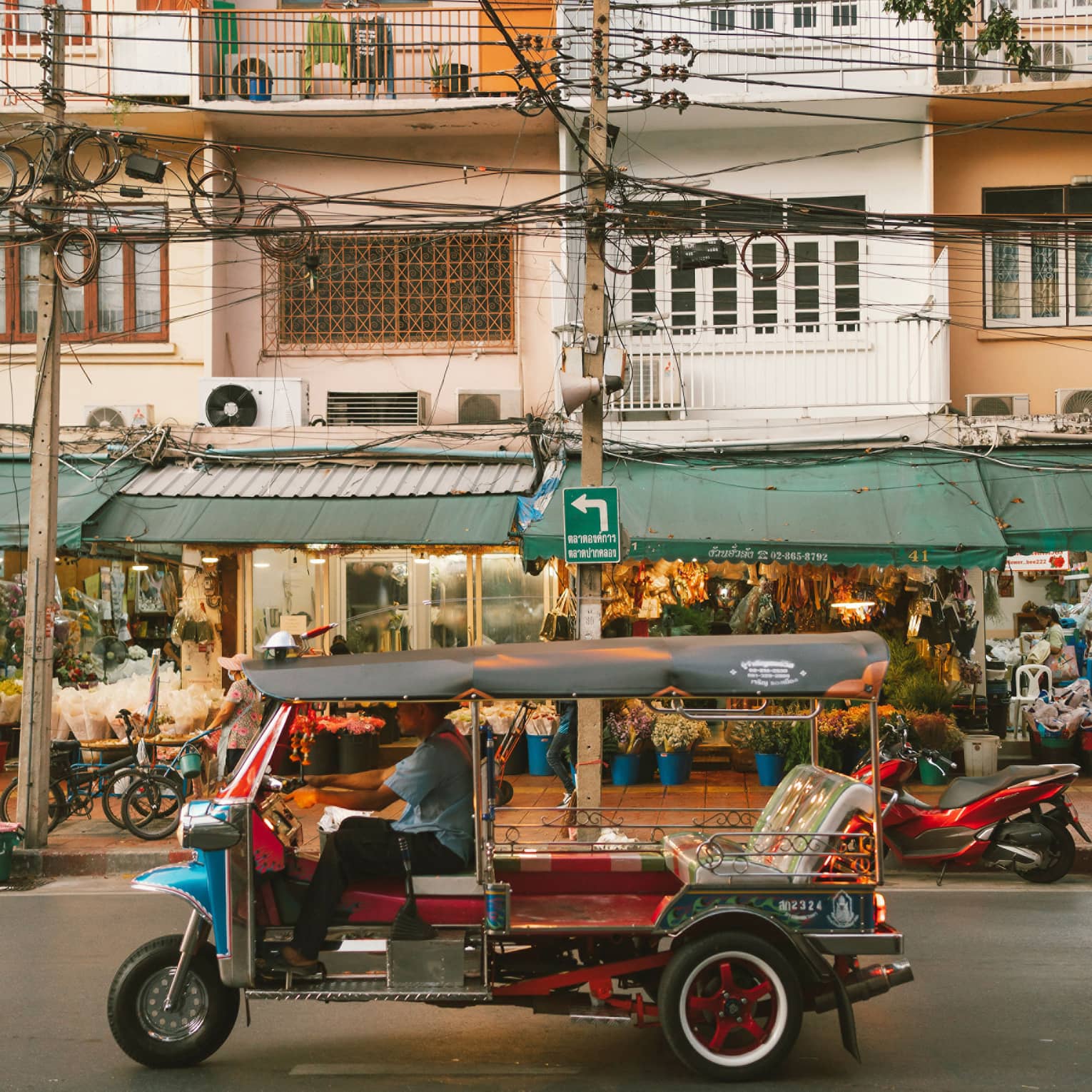 Colourful auto rickshaw parked in front of three-storey building with green awning