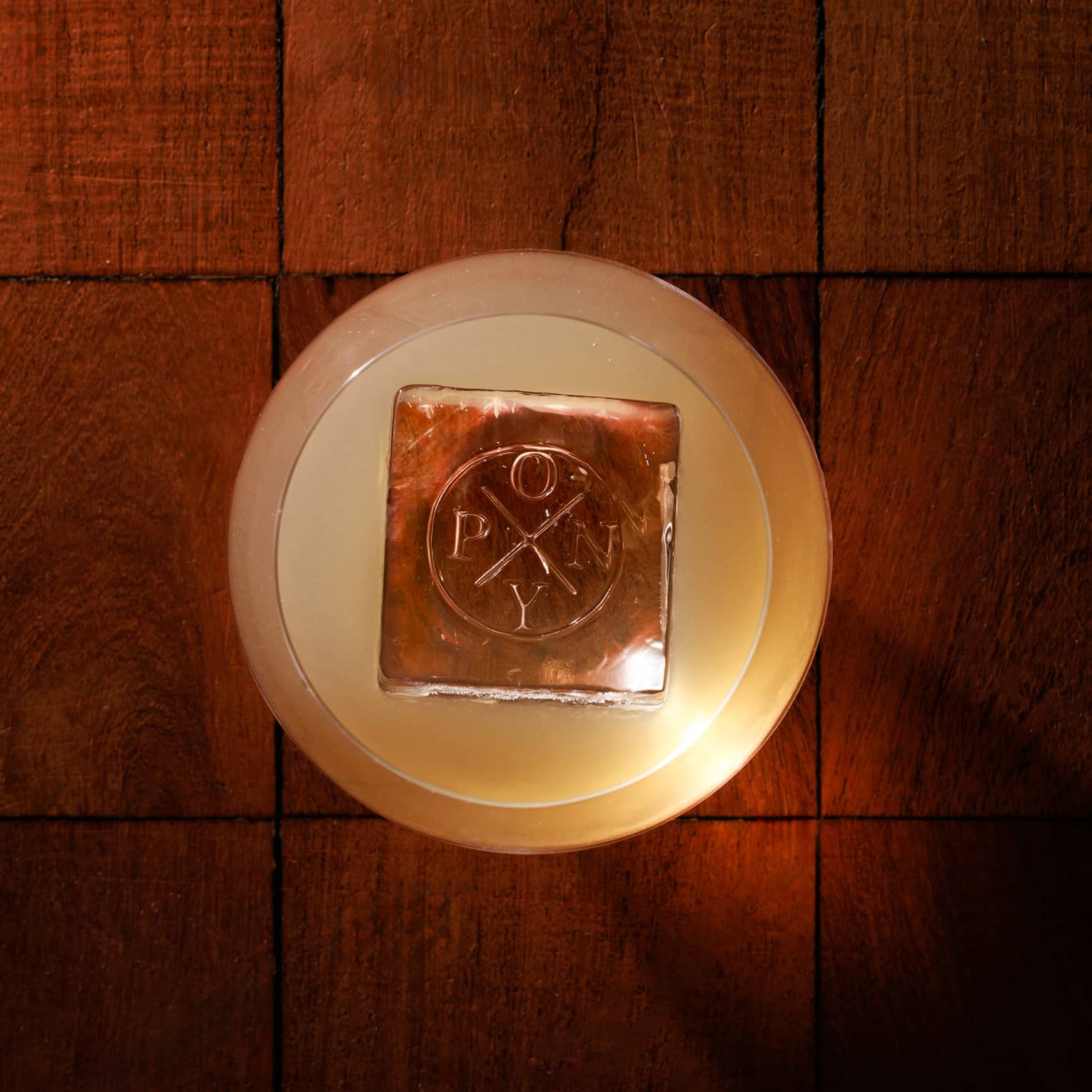 Overhead view of a cocktail with a large ice cube branded with the word "Pony"