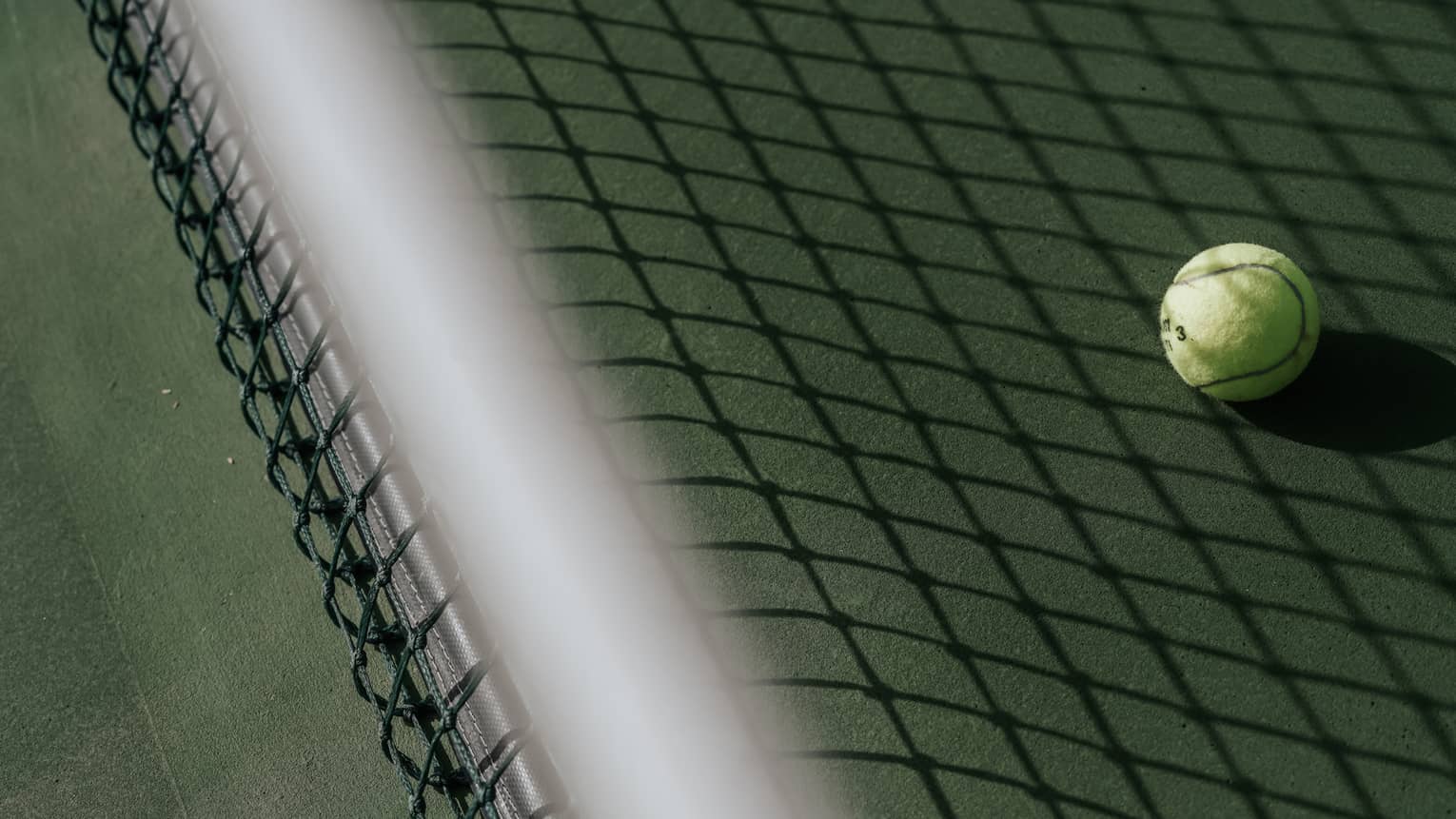 Tennis ball on tennis court with shadow of net