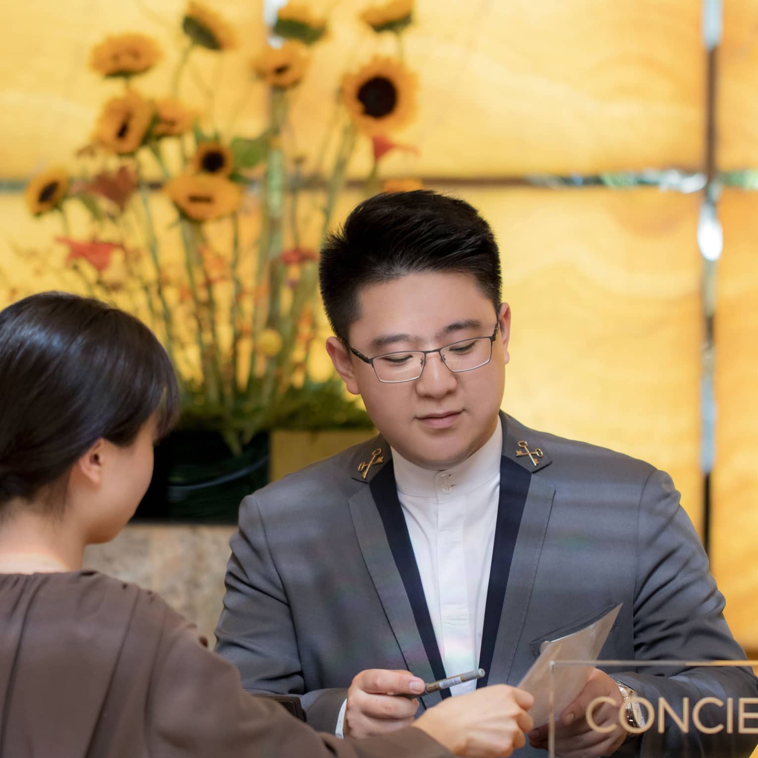 A concierge assists a guest at a marble desk