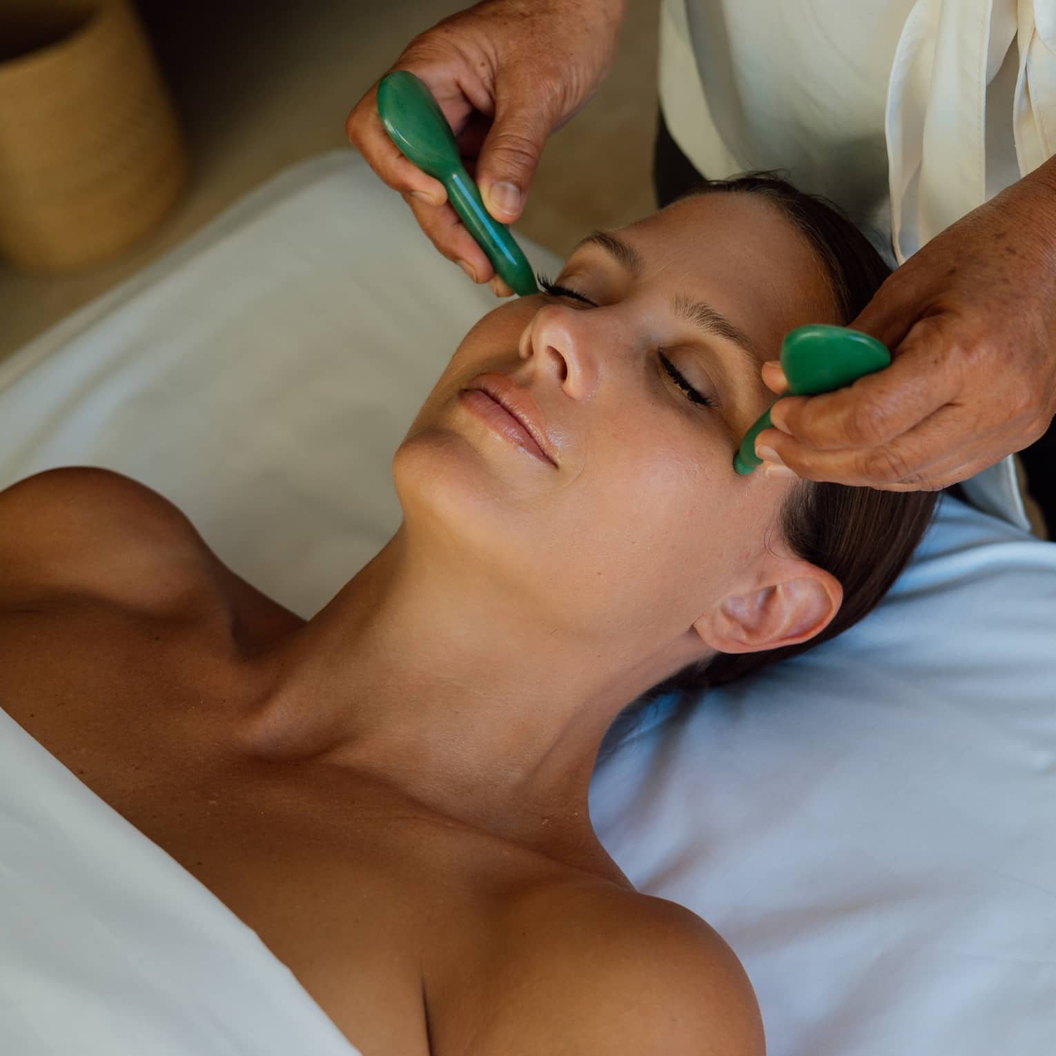 Guest getting a face massage while laying on a massage table.