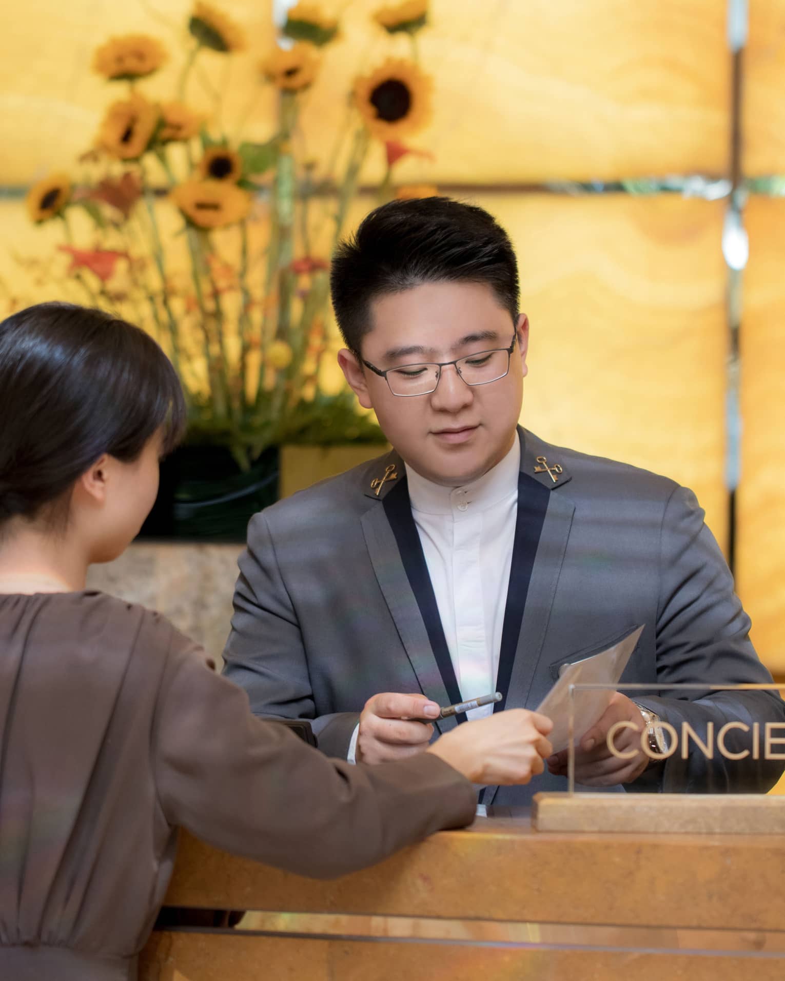 A concierge assists a guest at a marble desk