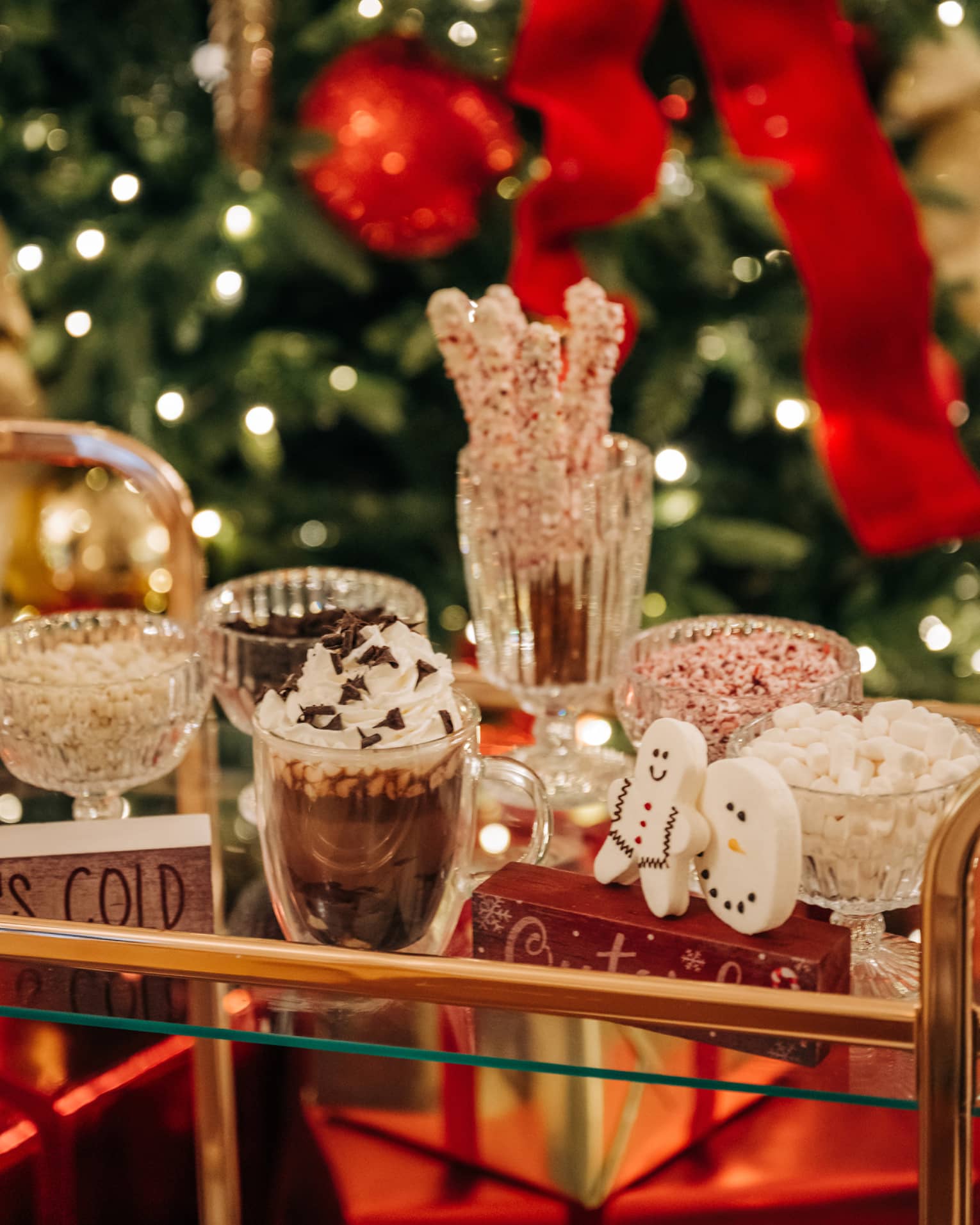 Gold and glass beverage cart carrying hot chocolate and festive toppings