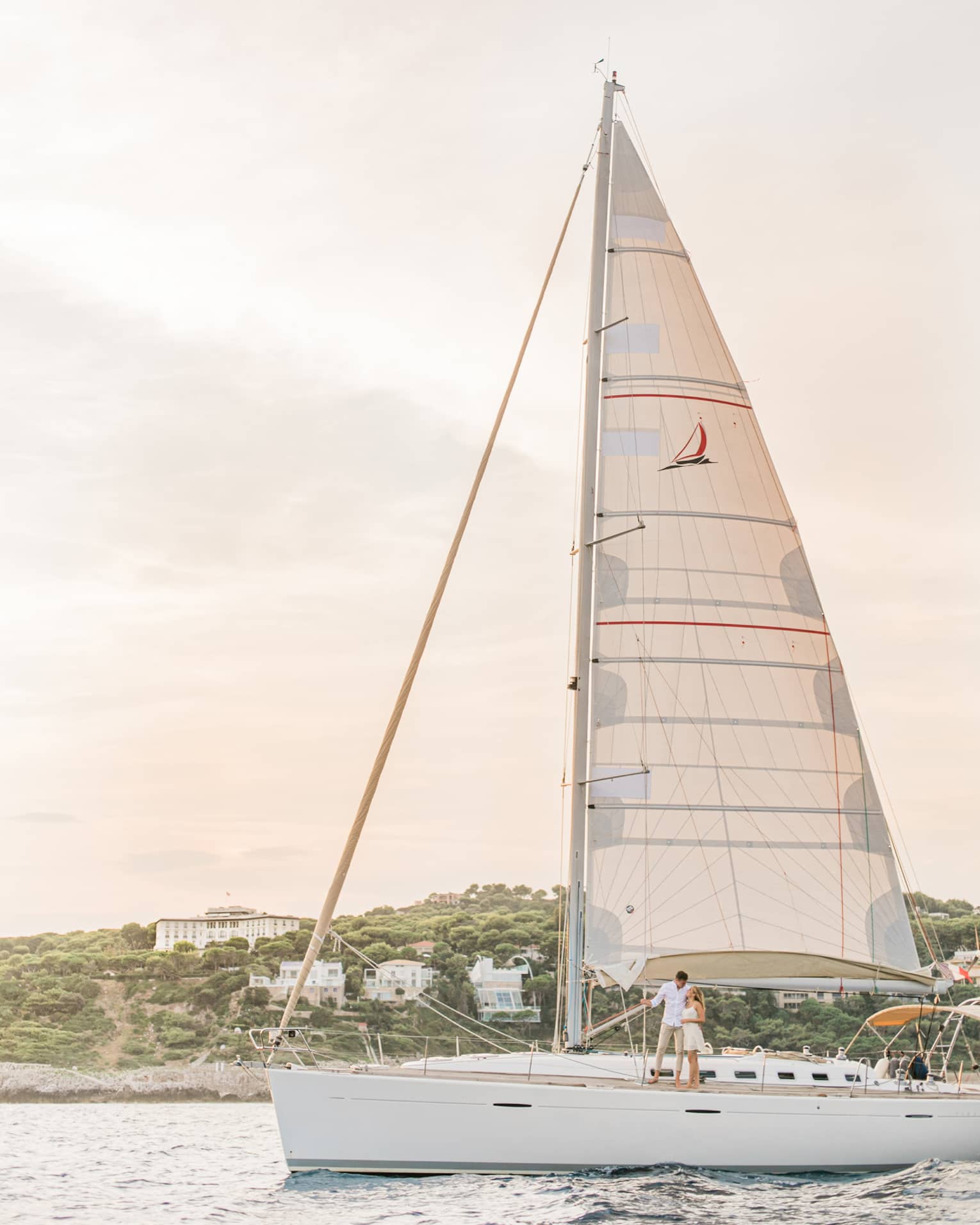 White sailboat on water in front of island with white buildings