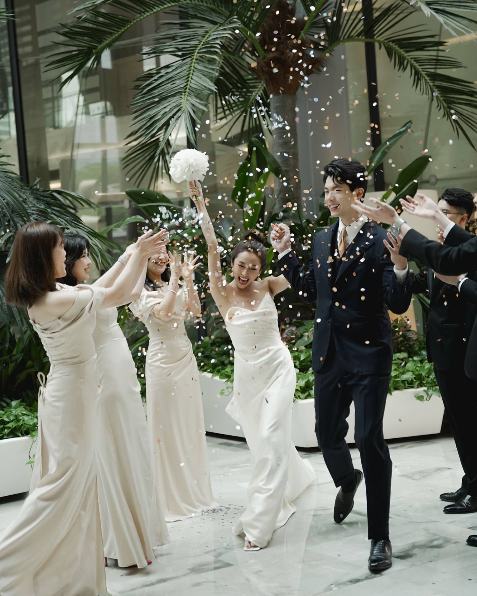 Wedding party members toss flower petals at newly married couple as they walk down the aisle