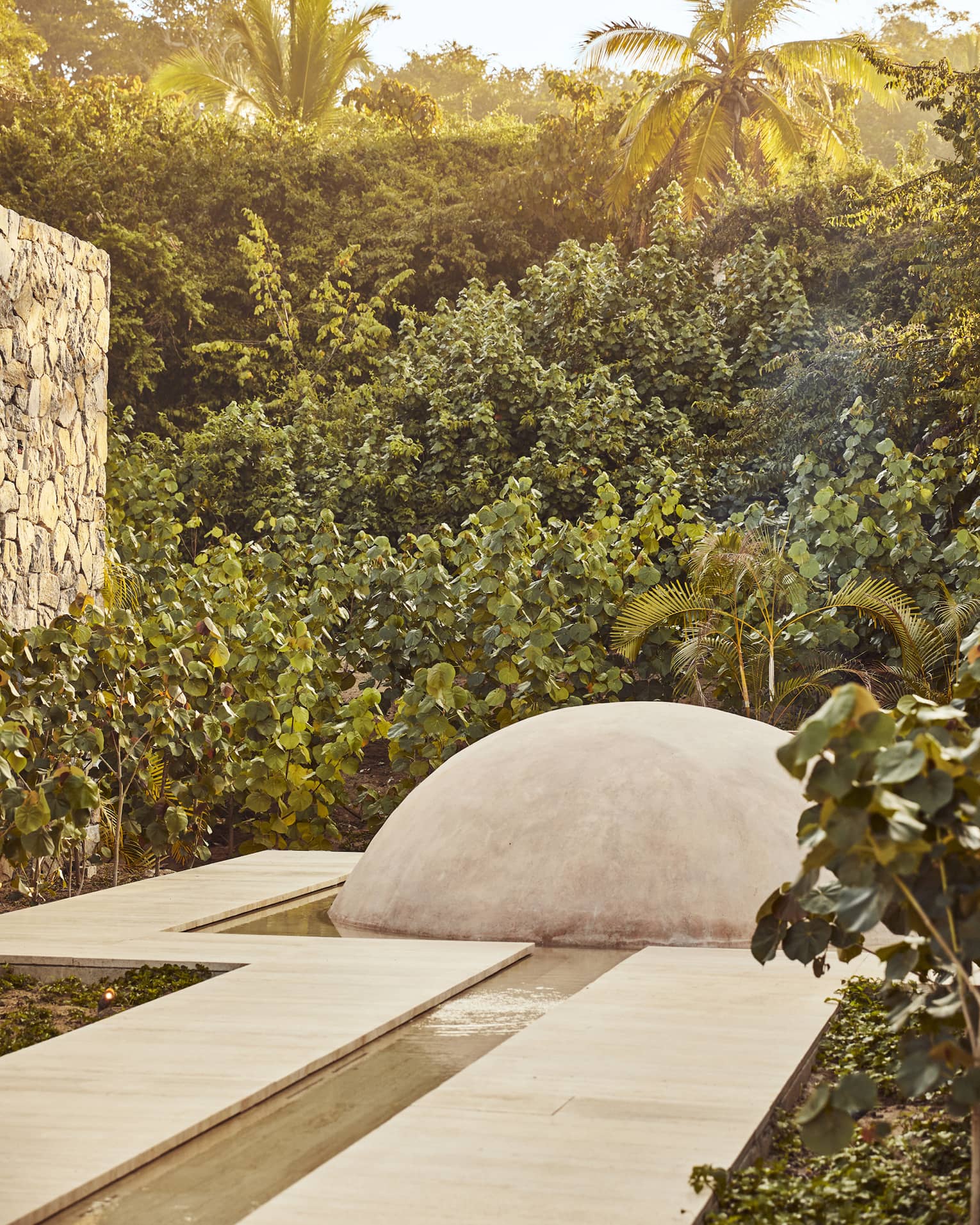Pathway that leads to a dome surrounded by trees and leaves.