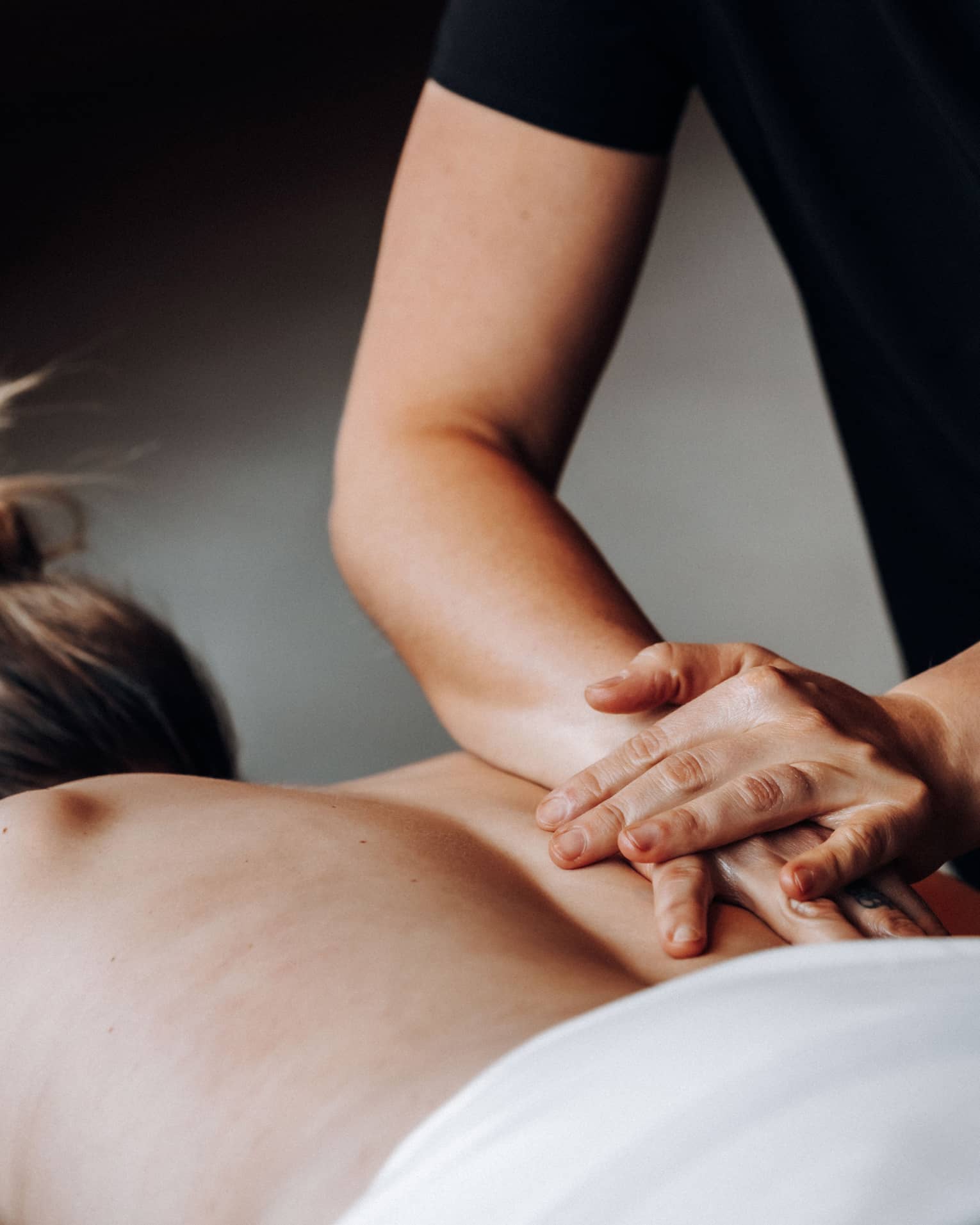 Massage therapists rubs a person's bare back with one hand placed on top of the other