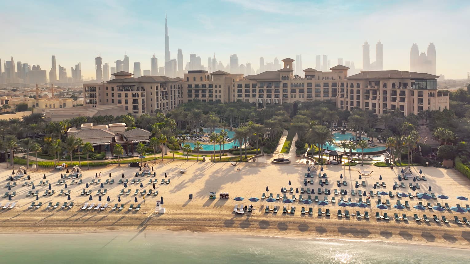 An overhead shot of a resort with lines of beach chairs in front of the bay.