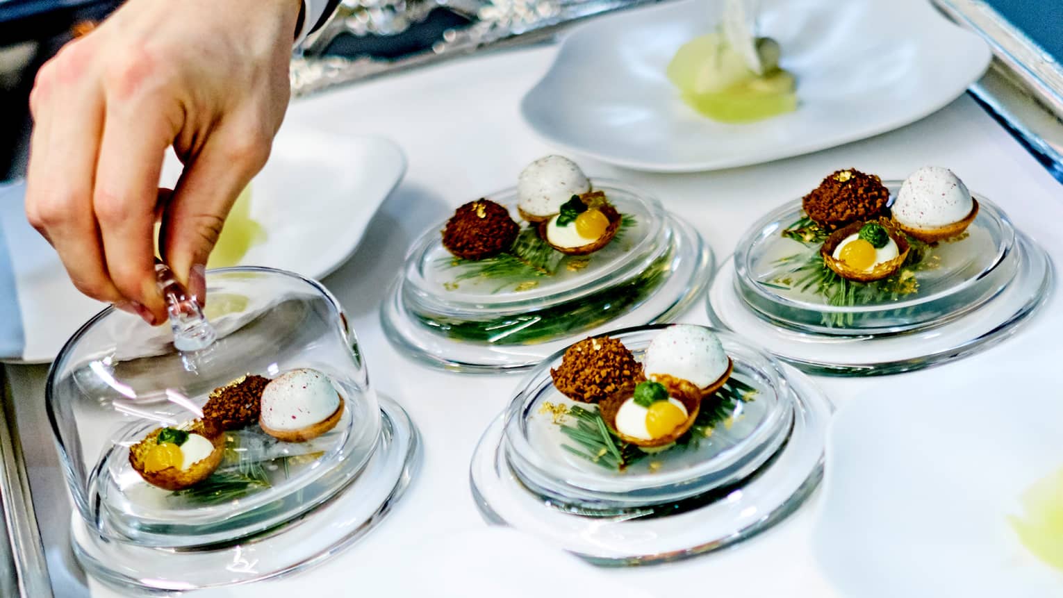 Close-up of chef garnishing small egg dishes