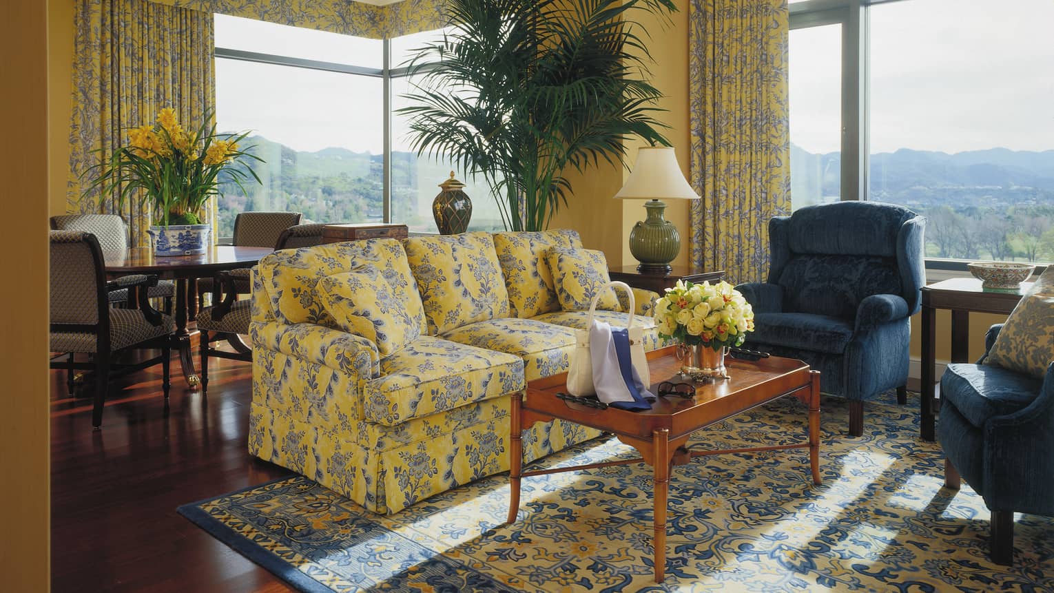 One-bedroom suite blue and yellow floral sofa, armchair, coffee table with purse, sunglasses