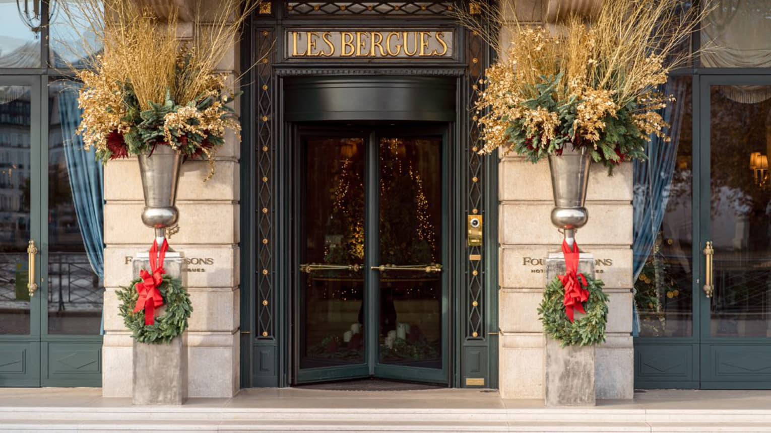 The doors to a hotel with wreaths next to them.