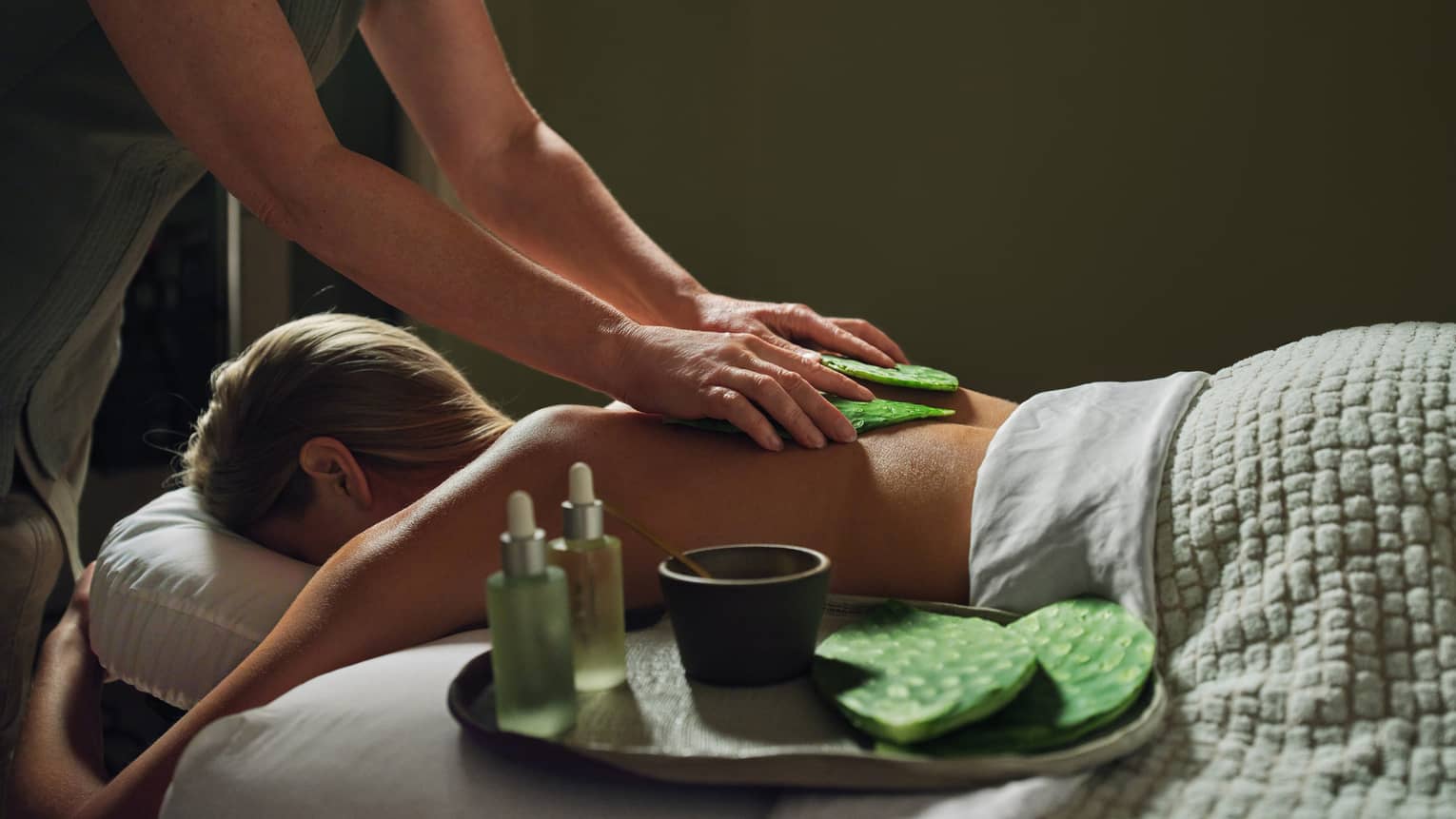 Guest laying on massage table with a blanket while getting a back massage.