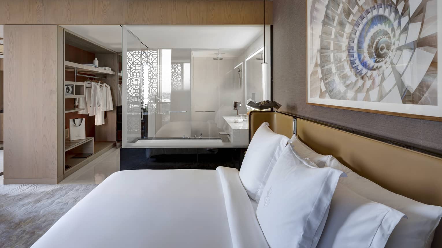 Bedroom with king bed, artwork hanging above, open bathroom