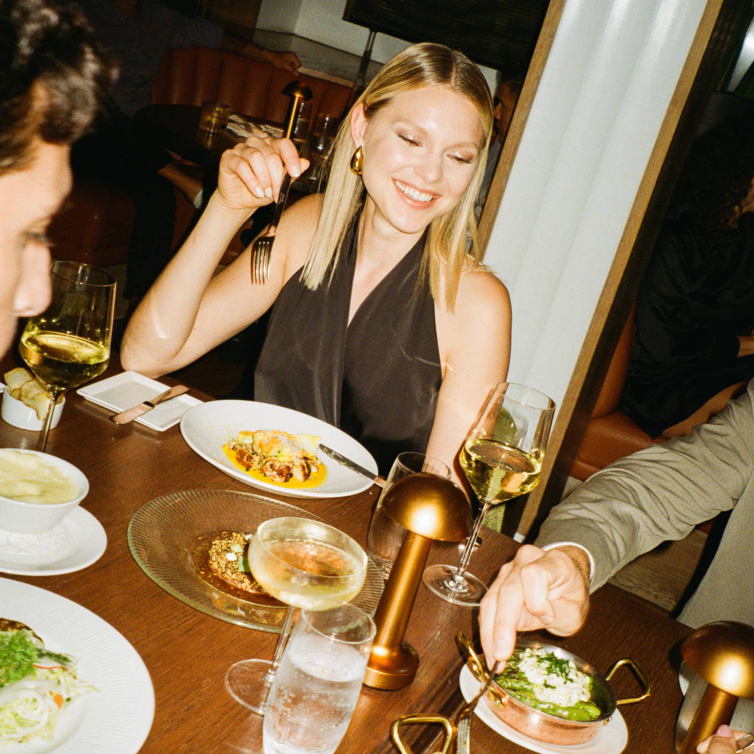 Friends eat at dining table together, with shared plates in small copper dishes