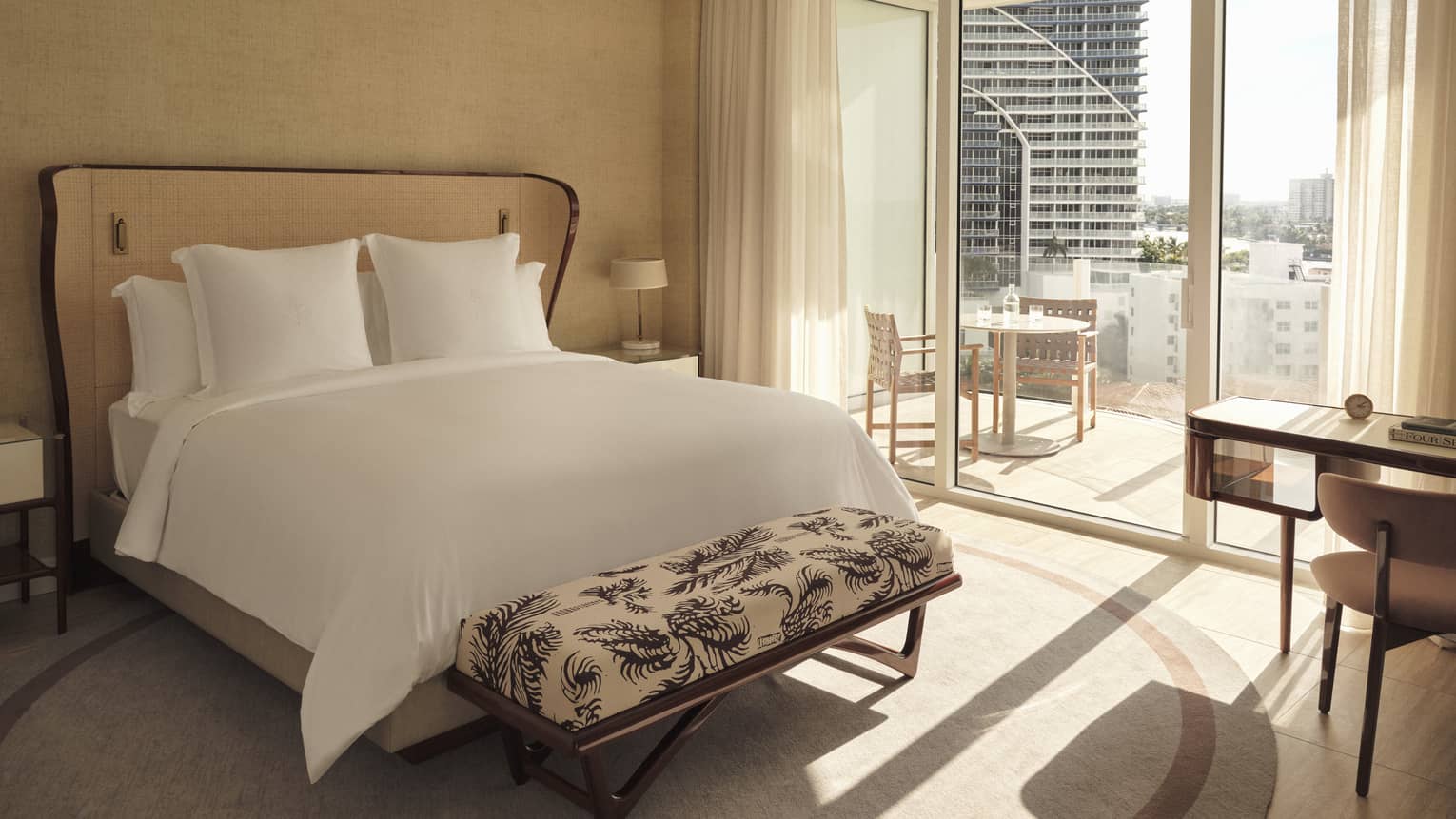 Hotel room with king bed, bench, glass doors to balcony