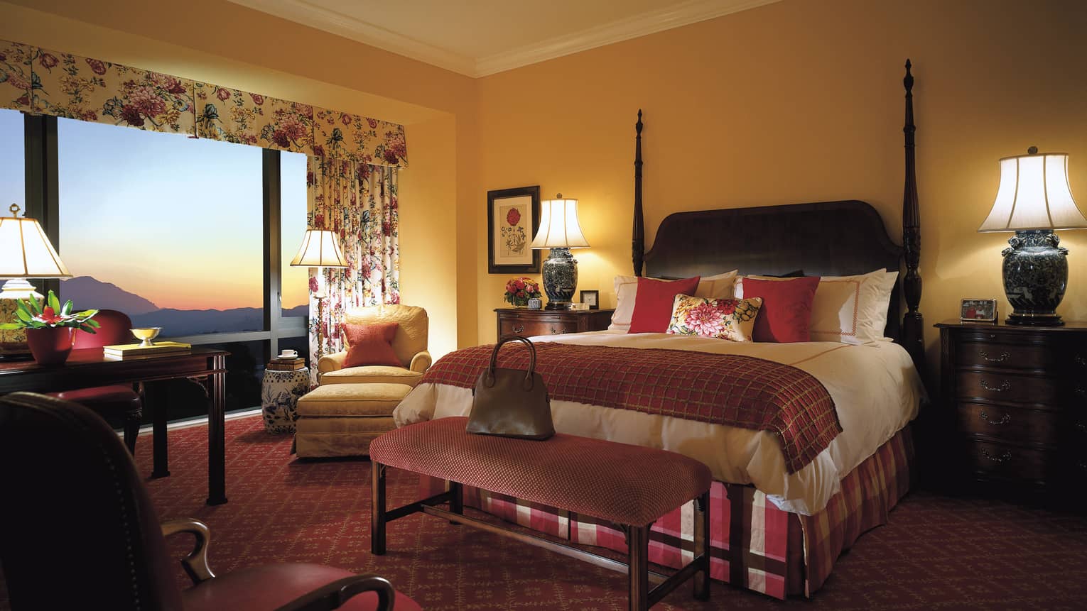 Superior Room poster bed, red pillows, accents, desk by picture window, sunset views