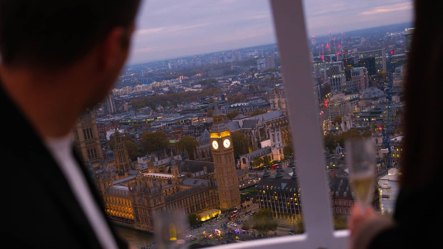 People look out over a city from above from a capsule on a large ferris wheel.