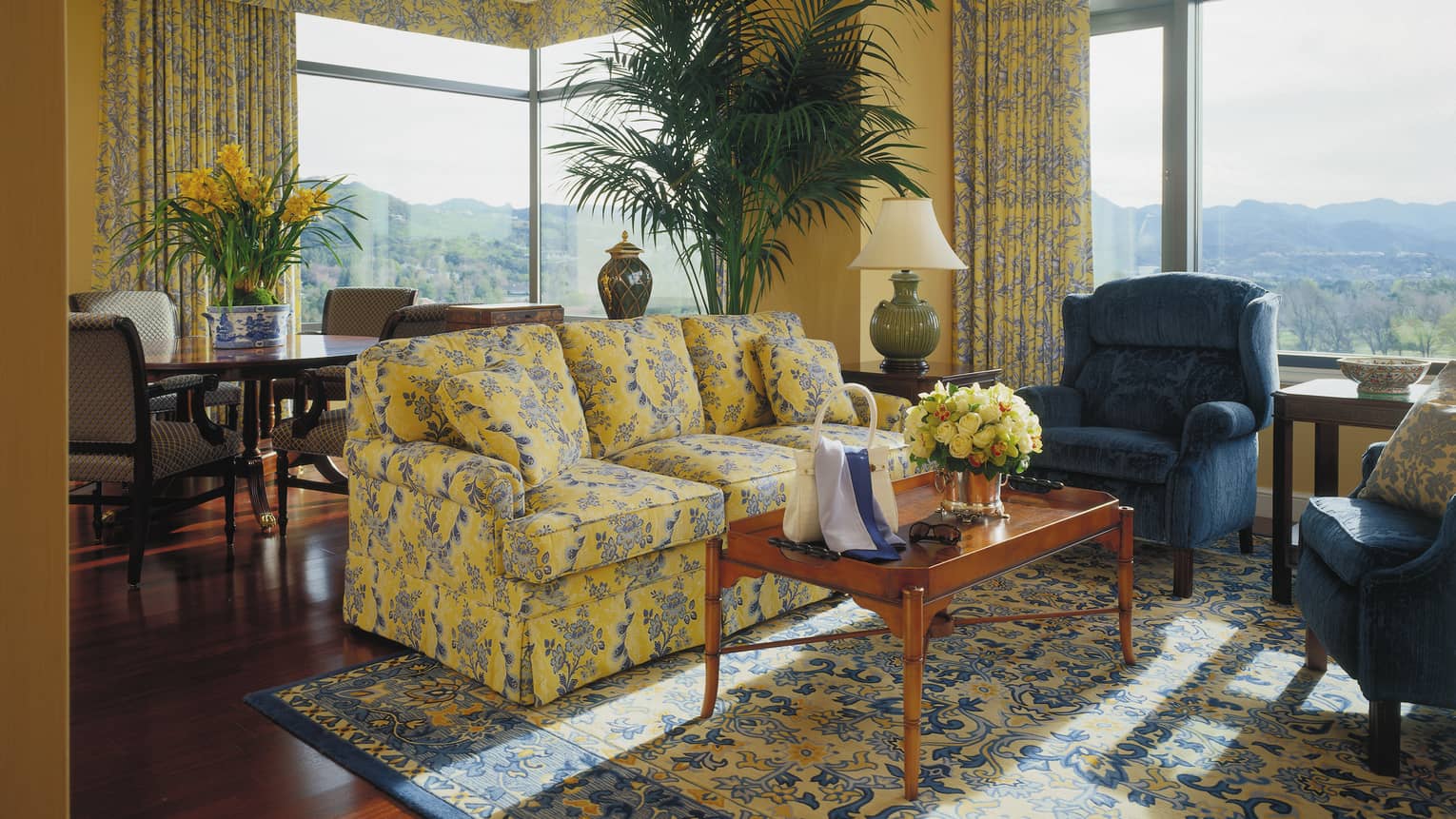 One-bedroom suite blue and yellow floral sofa, armchair, coffee table with purse, sunglasses