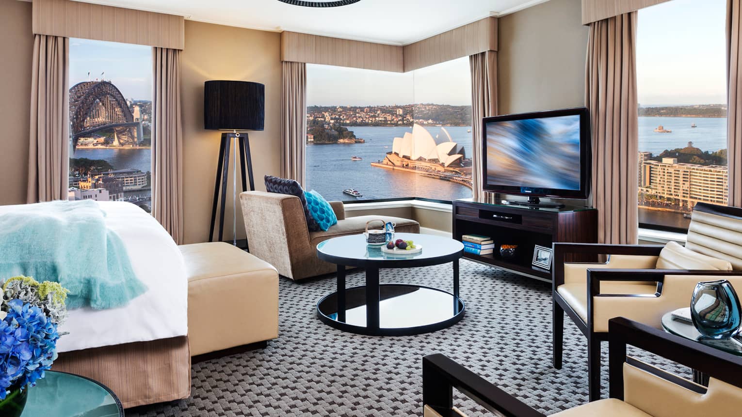 Hotel room seating area with corner windows overlooking Sydney Opera House, harbour