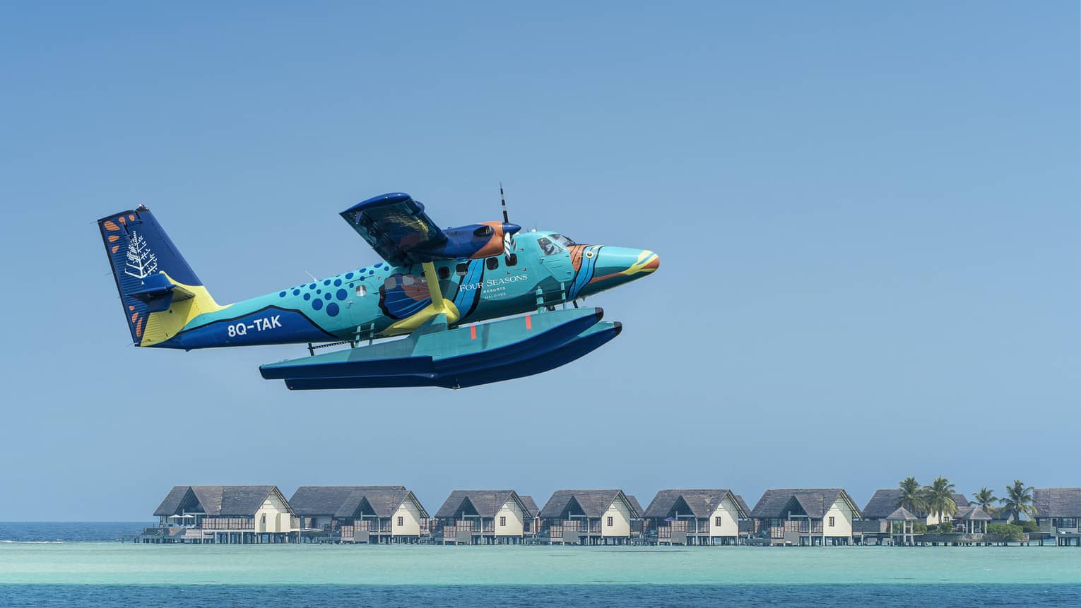 Maldives Sea Plane taking off with water villas and palm trees in the background