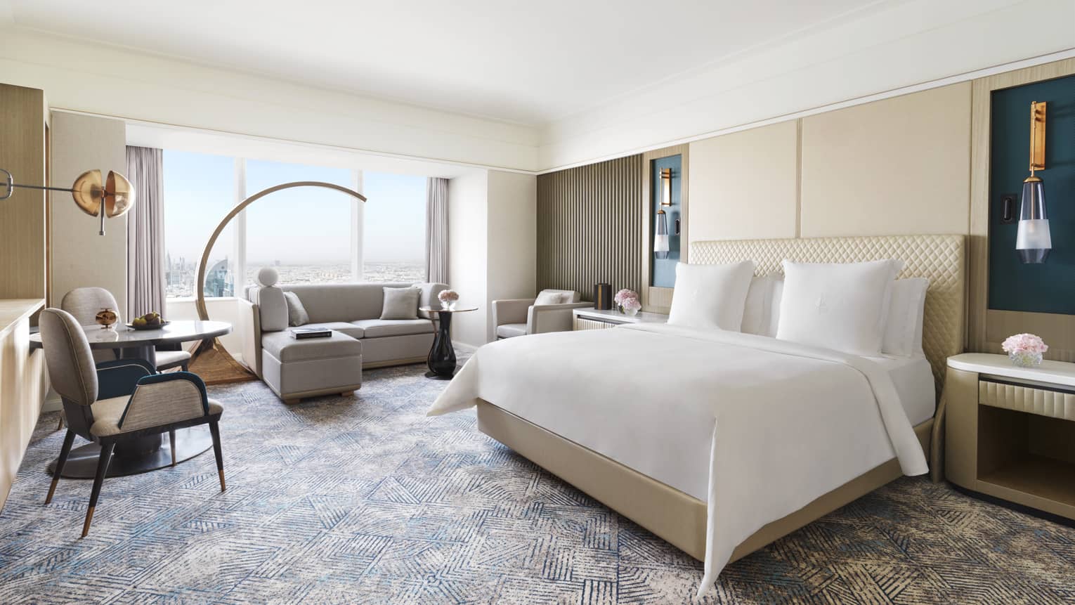 Hotel room with king bed, window-side sofa, and small table with two chairs