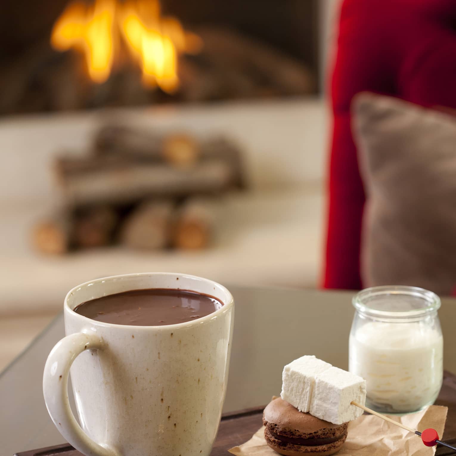 Hot chocolate in large mug beside marshmallow skewer, macaron