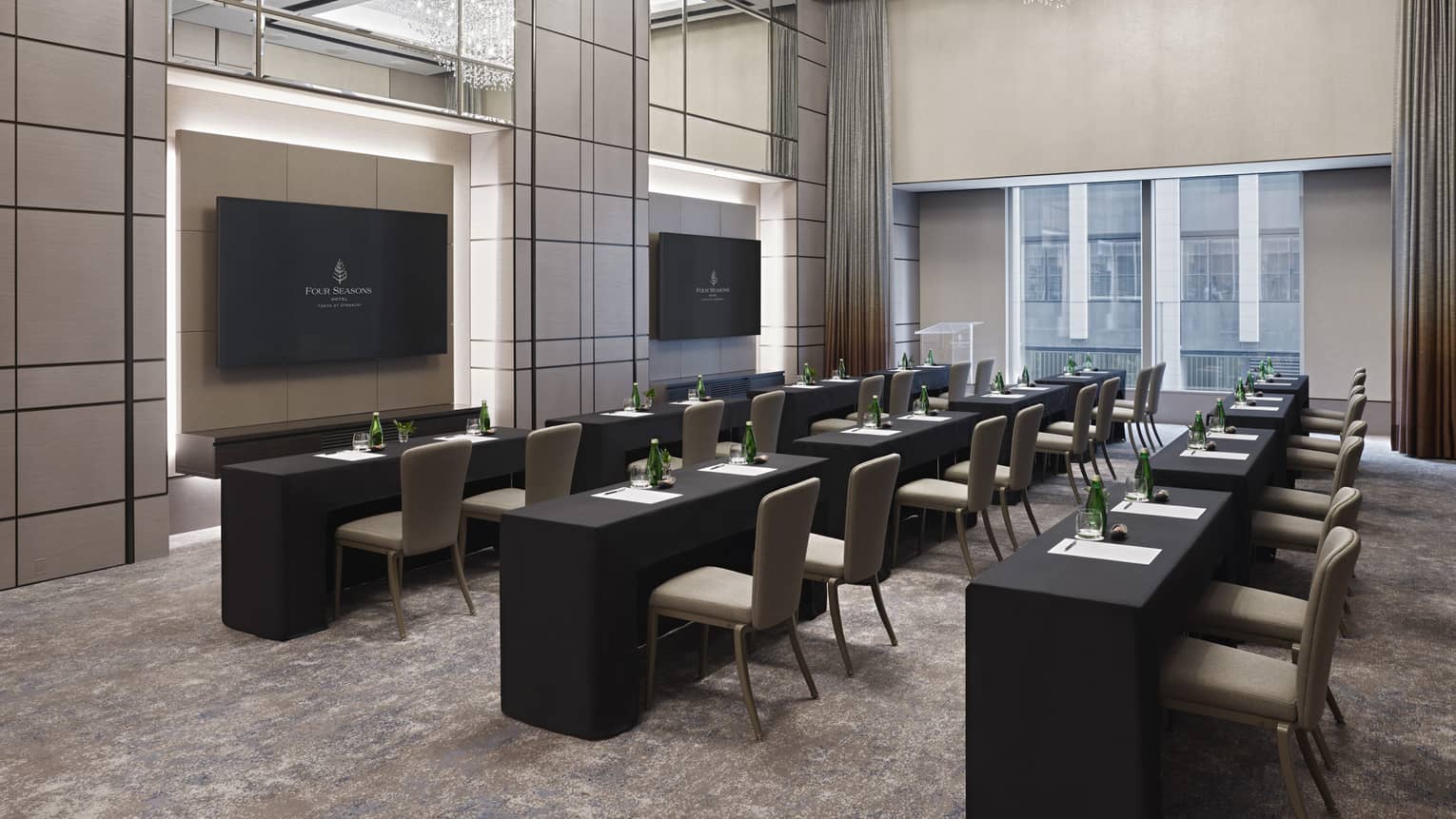 Meeting room set classroom-style with double chandeliers, black linens and two presentation screens 