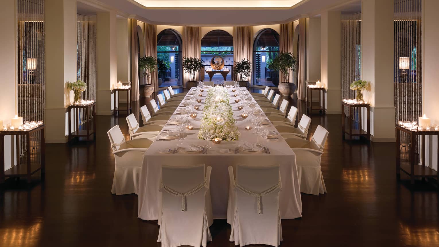 Long banquet wedding dining table with white floral centrepiece, tea lights in small copper bowls