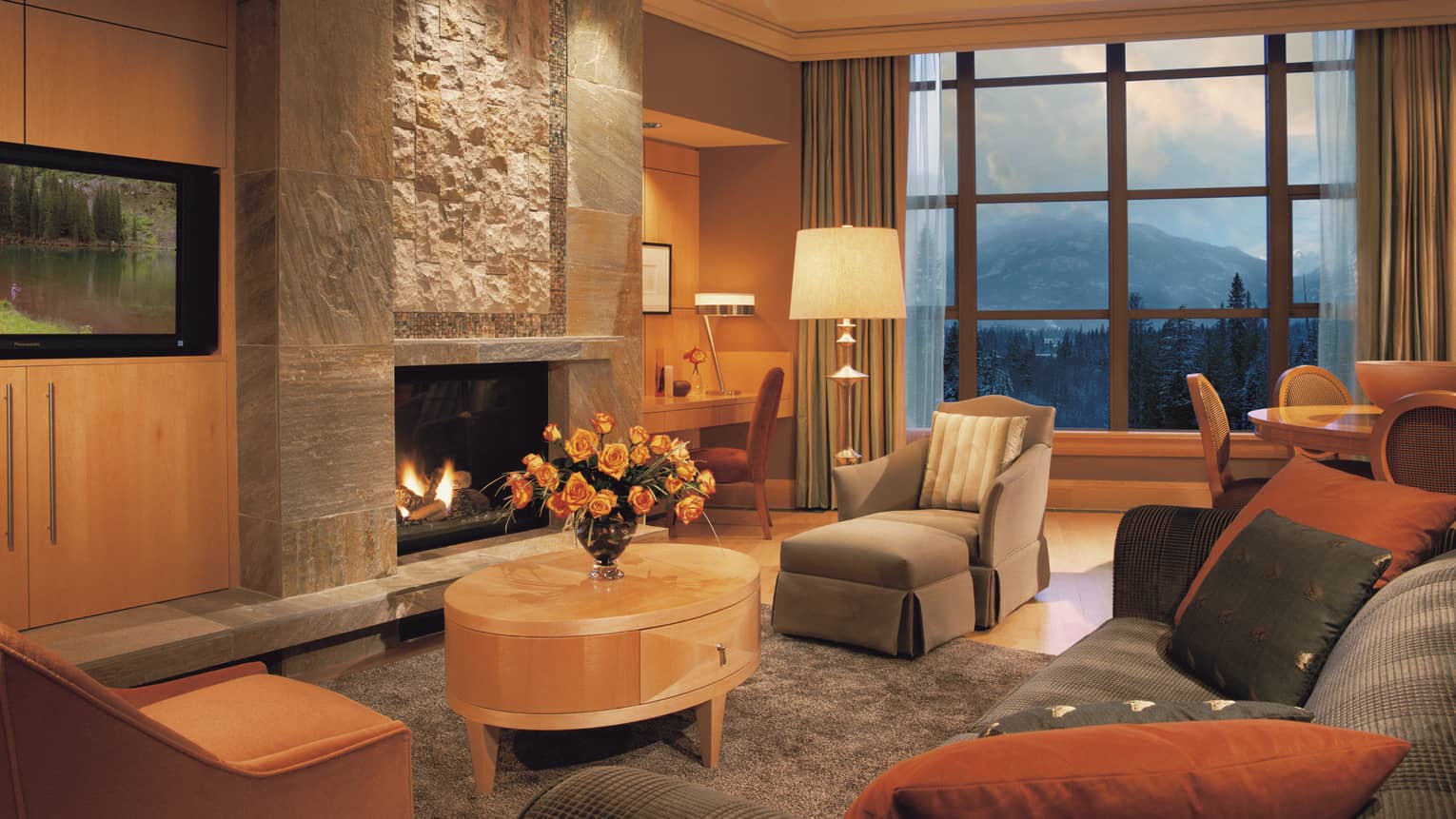 Resort residence living room with grey chaise chair, sofa, table in front of tall stone gas fireplace