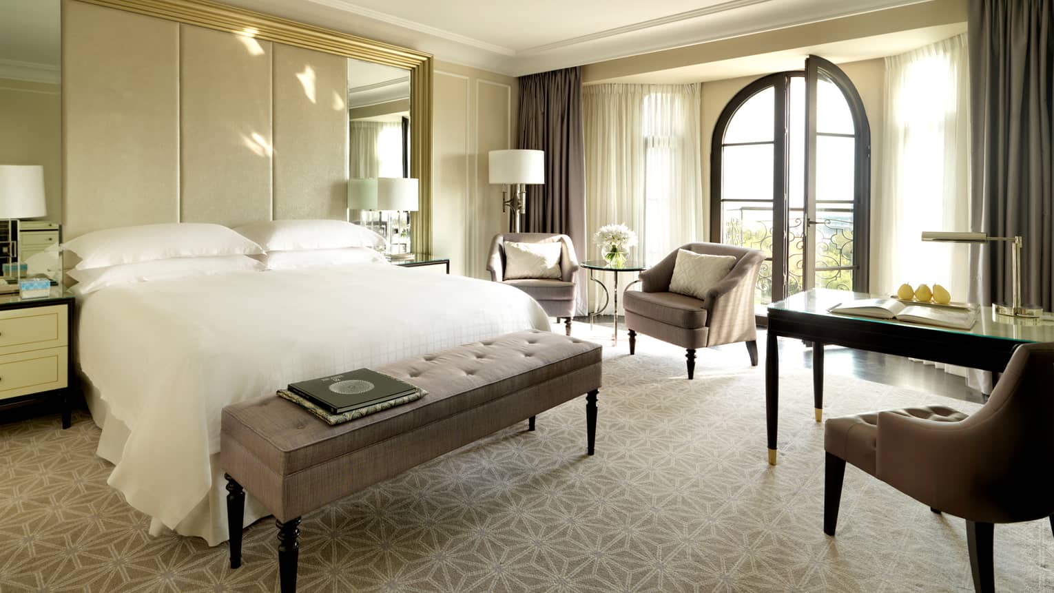 Deluxe Caspian Room, books on plush bench at foot of bed, tall padded headboard and mirrors, chairs, French balcony