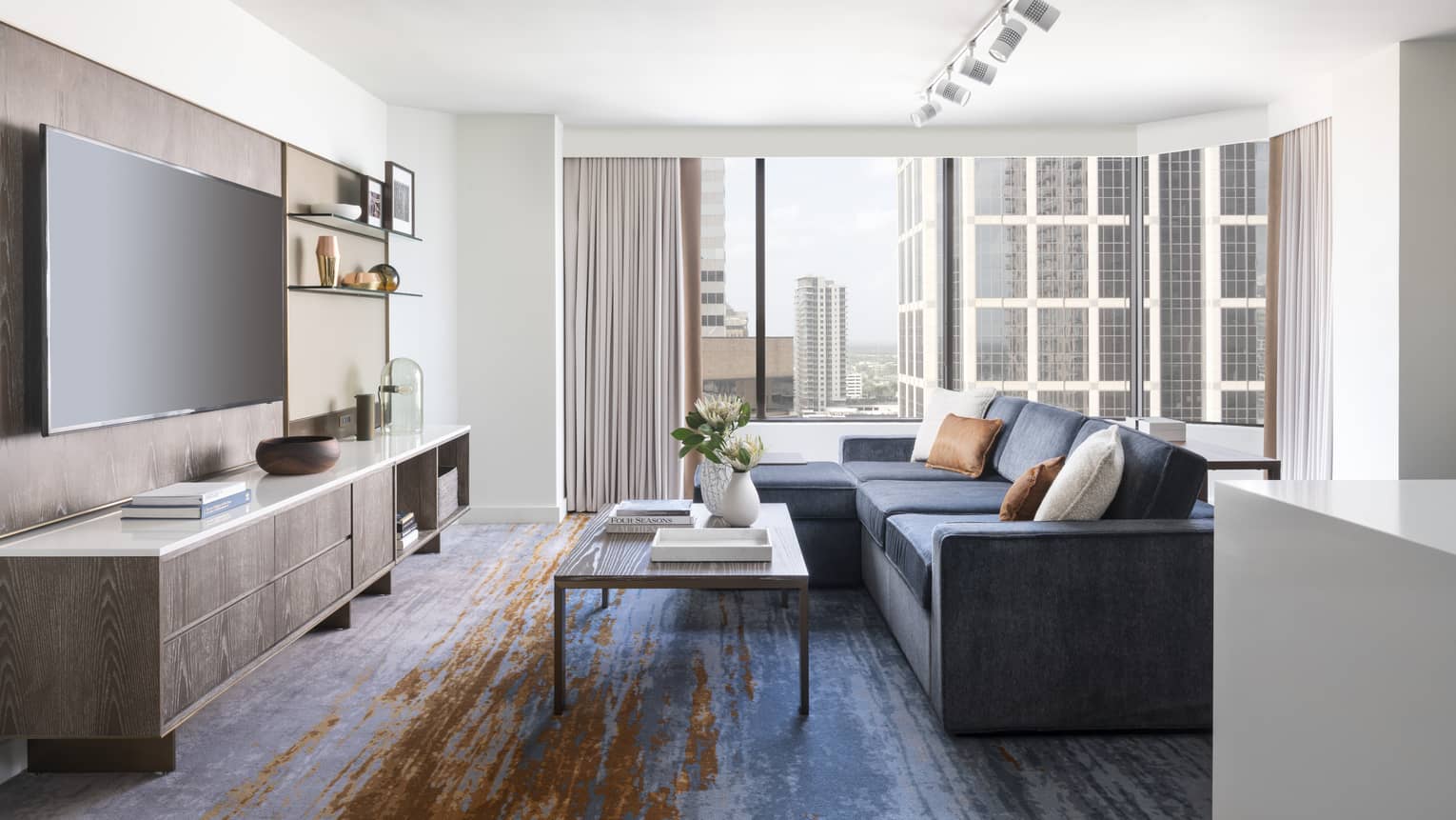 Two-bedroom Residential Suite living area with navy sectional sofa, floor-to-ceiling windows, city views