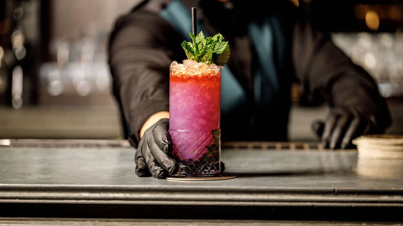 A pink and red high ball cocktail with crushed ice and mint