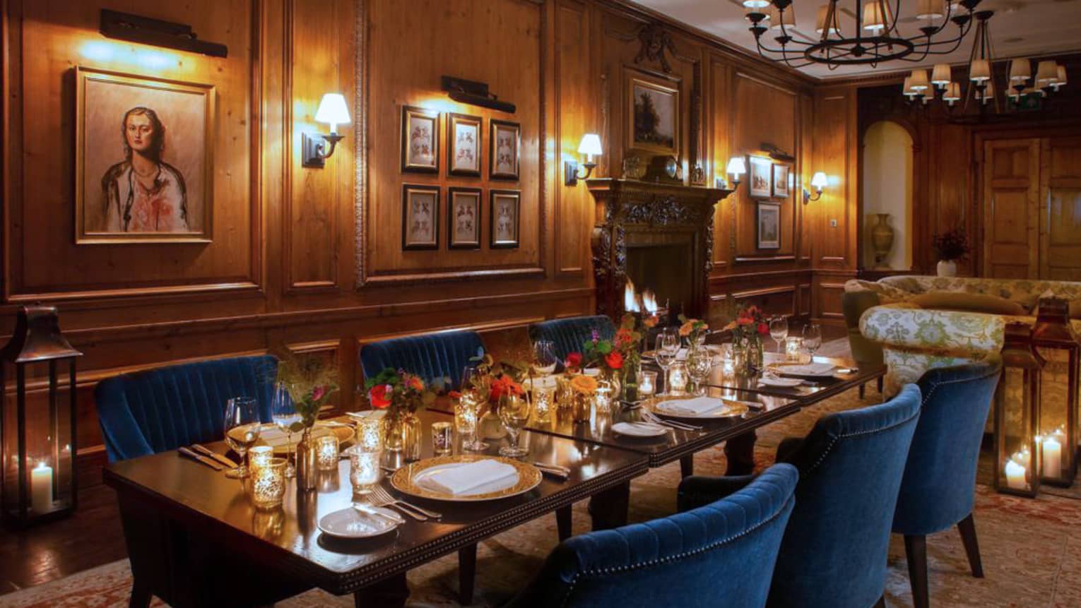 Elegantly set dining table with blue velvet chairs in historic wood-panelled room