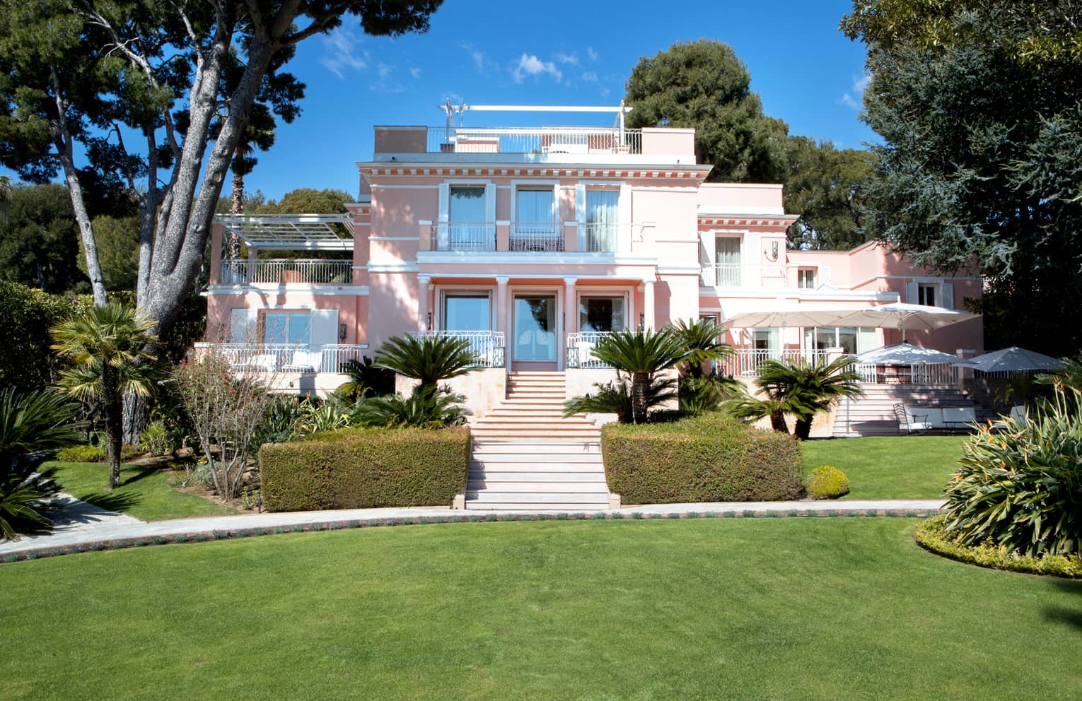 Manicured gardens, steps up to large three-storey pink Villa Rose-Pierre