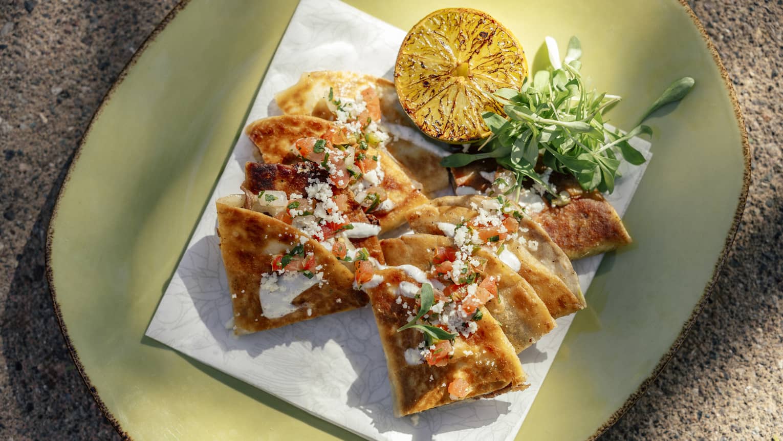 Quesadilla cut into wedges with greens and grilled citrus