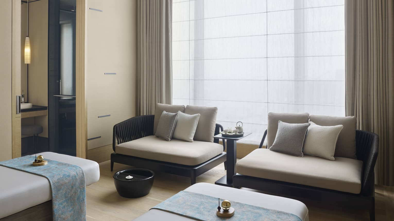 Couples Treatment Room, two spa treatment beds and small sofas under tall window