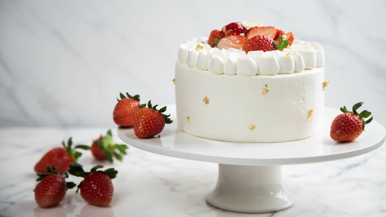 Single-tier seasonal fruit cake with fresh strawberries on white cake stand